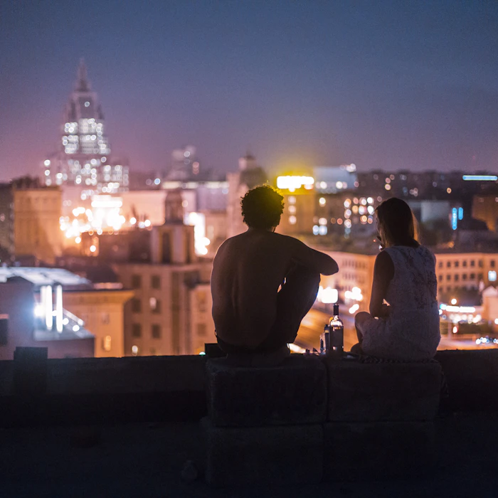 Two friends relaxing on a rooftop in front of Mumbai high-rise buildings
